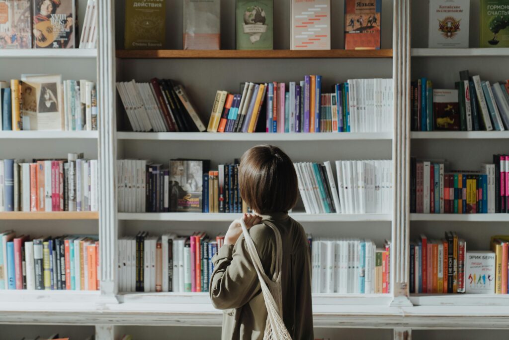 pexels-photo-4855385-4855385-1 A woman browsing a bookshelf in a well-lit bookstore, exploring various titles.
